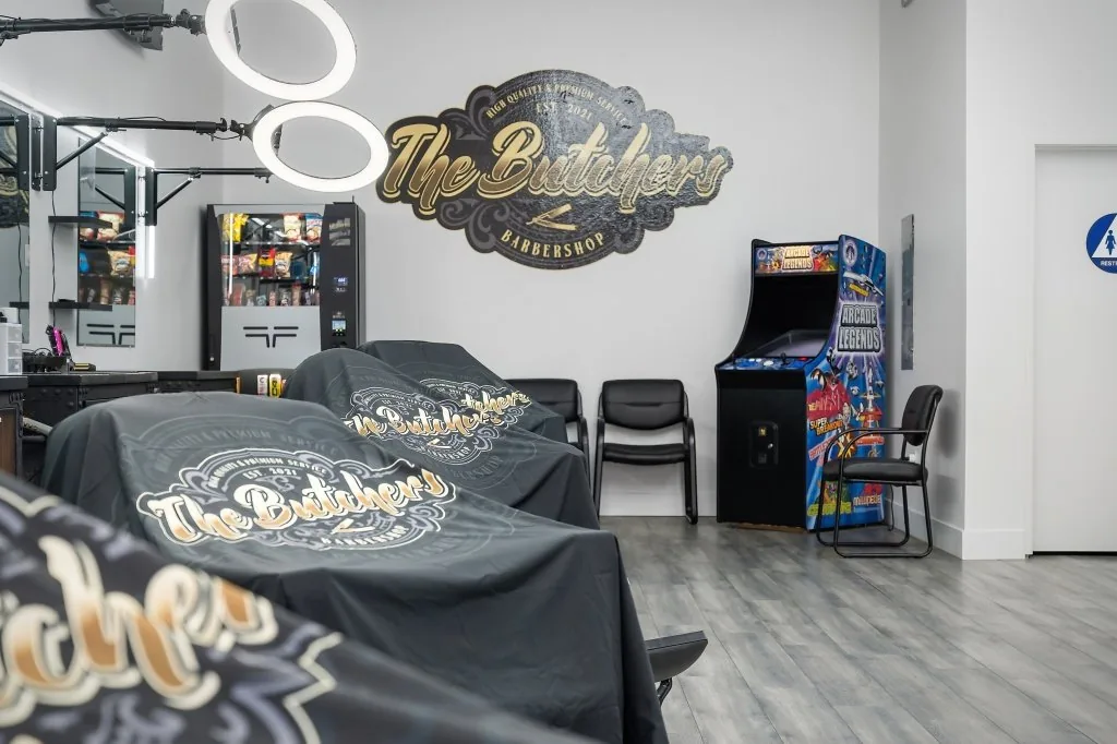 Cutting floor — styling stations with ring lights and the gold crest wall inside The Butchers Barbershop