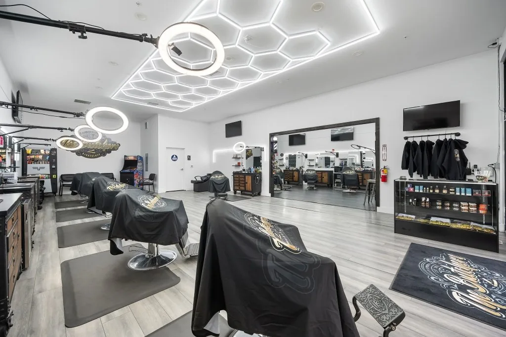 Caped barber chair ready at the station under the hex LED ceiling