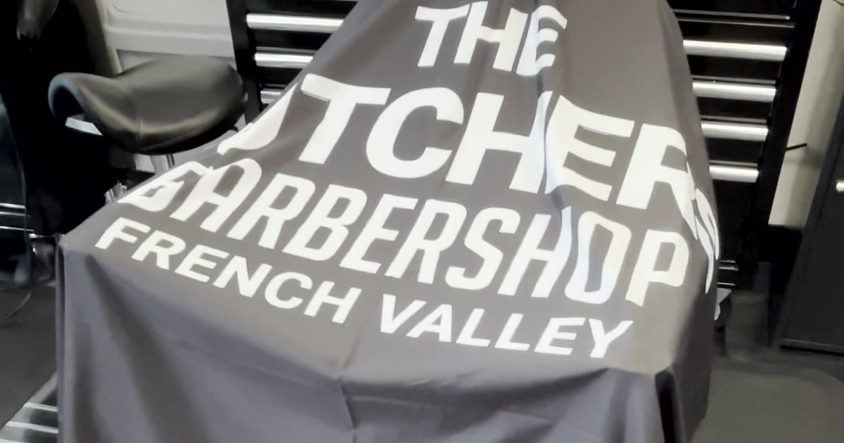 Branded cape draped over the barber chair inside the French Valley shop — The Butchers Barbershop lettering fills the frame