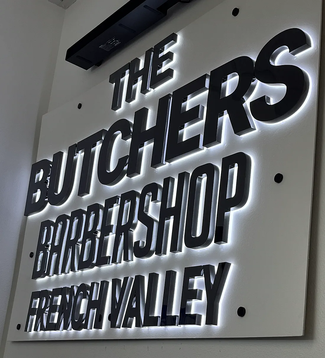 The Butchers Barbershop sign at the French Valley shop — dimensional black lettering with halo lighting