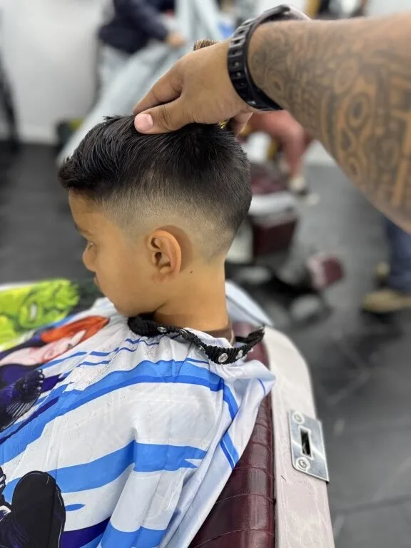Boy's fade haircut in the chair — short faded sides with a longer side-swept top