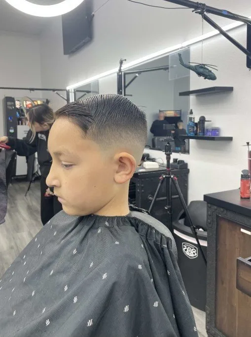 Young client in profile showing a fresh taper — clean edge-up and a combed top
