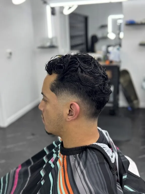 Client in profile showing a fresh skin fade — clean temple blend and a dark textured top