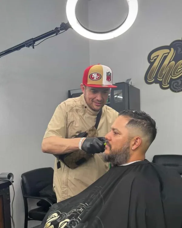 Rodney Moore Junior — barber at The Butchers Barbershop Murrieta — trimming a client’s beard